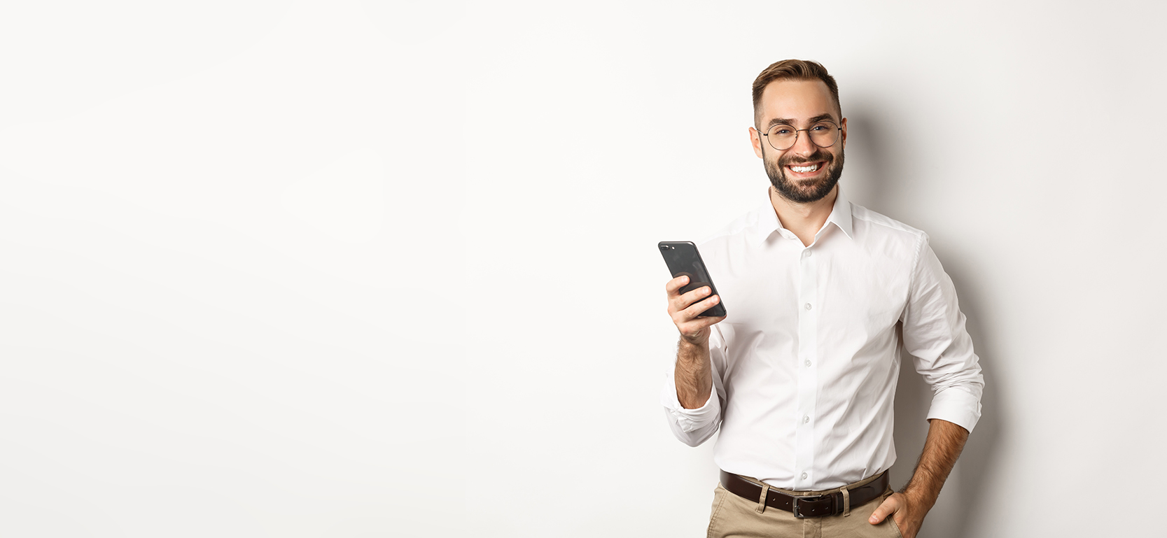 Gutaussehender Manager benutzt ein Smartphone und lächelt zufrieden, während er eine Textnachricht sendet, vor weißem Hintergrund