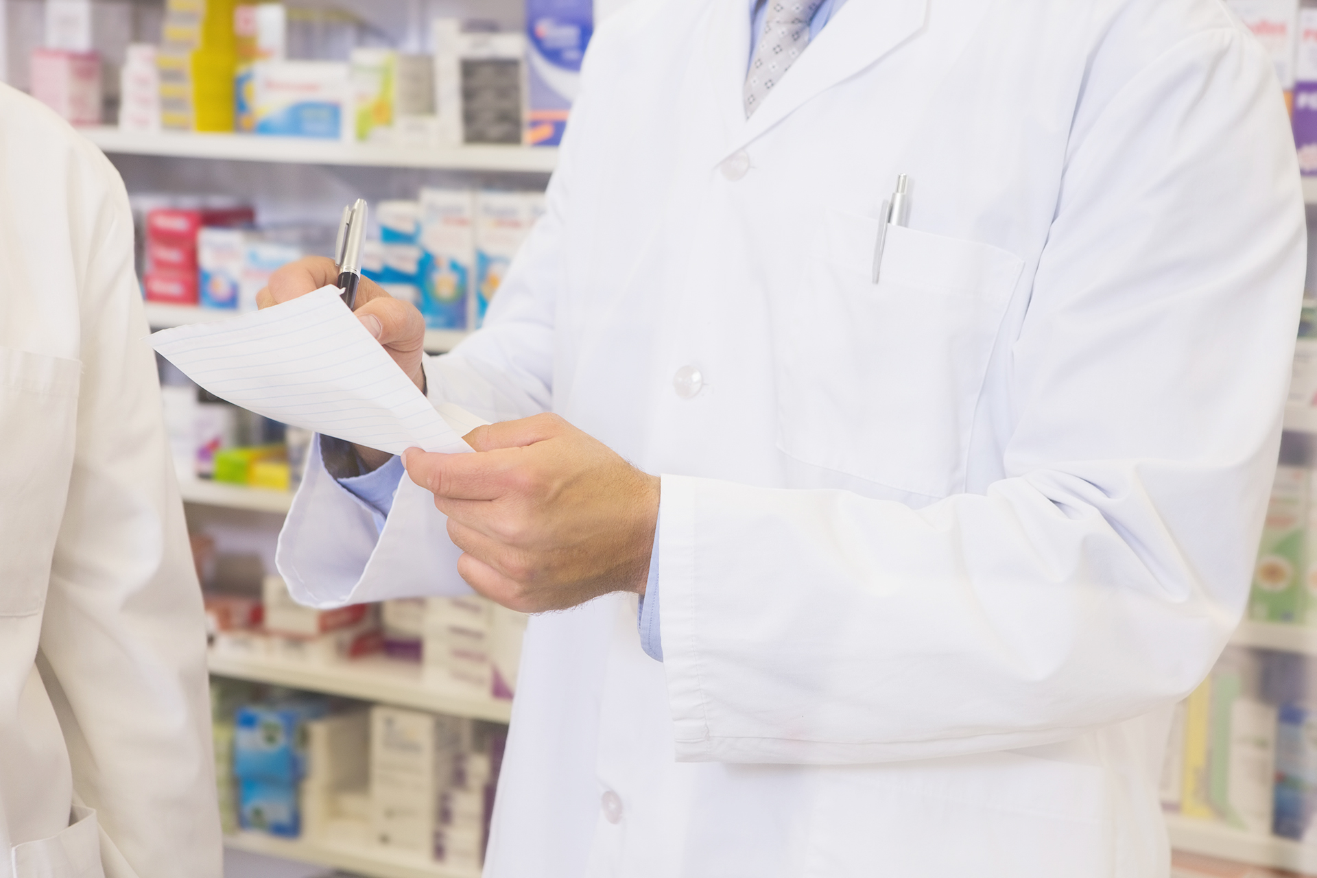 Oberkörper eines Apothekers beim Ausstellen eines Rezepts